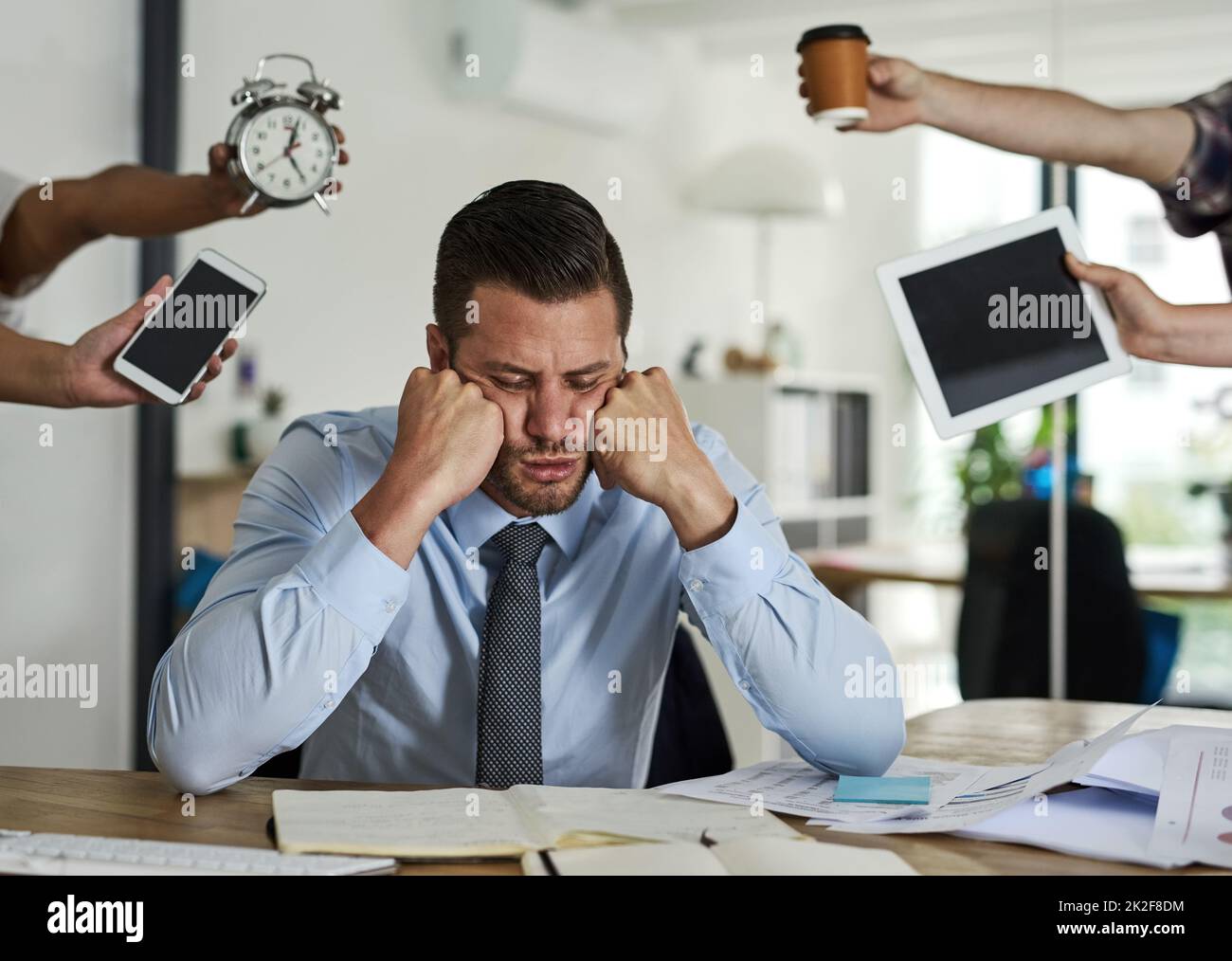Wishing his deadlines away. Shot of a stressed out businessman surrounded by demanding colleagues in an office. Stock Photo