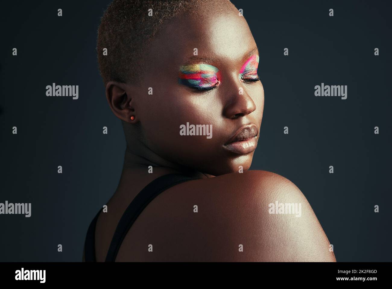 Be different, be unique. Cropped shot of a beautiful woman wearing colorful eyeshadow while posing against a grey background. Stock Photo