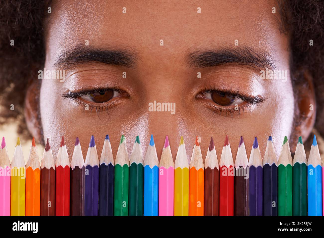 Hmm, so many colors.... Cropped view of an african man looking closely at a row of colorful pencil crayons. Stock Photo