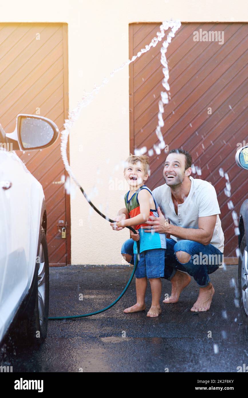 Full length shot of a father and son playing with a hosepipe while