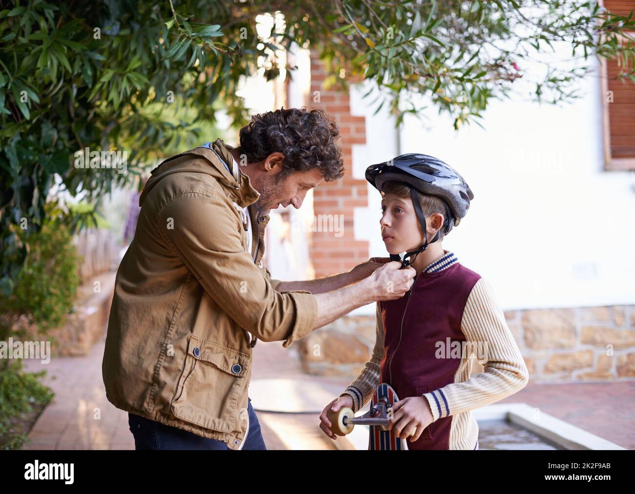 Be safe out there son. Shot of a father adjusting his sons helmet. Stock Photo