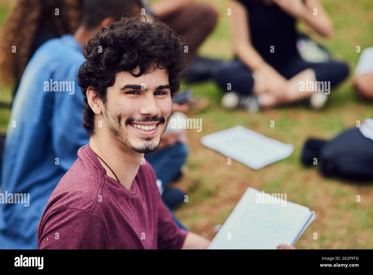 What a fun way to study. Portrait of a cheerful young man sitting in ...