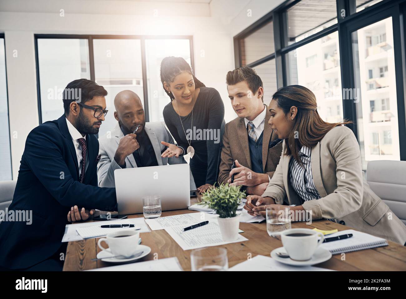 Business collaborations are what theyre best at. Shot of a group of young businesspeople using a laptop together during a meeting in a modern office. Stock Photo