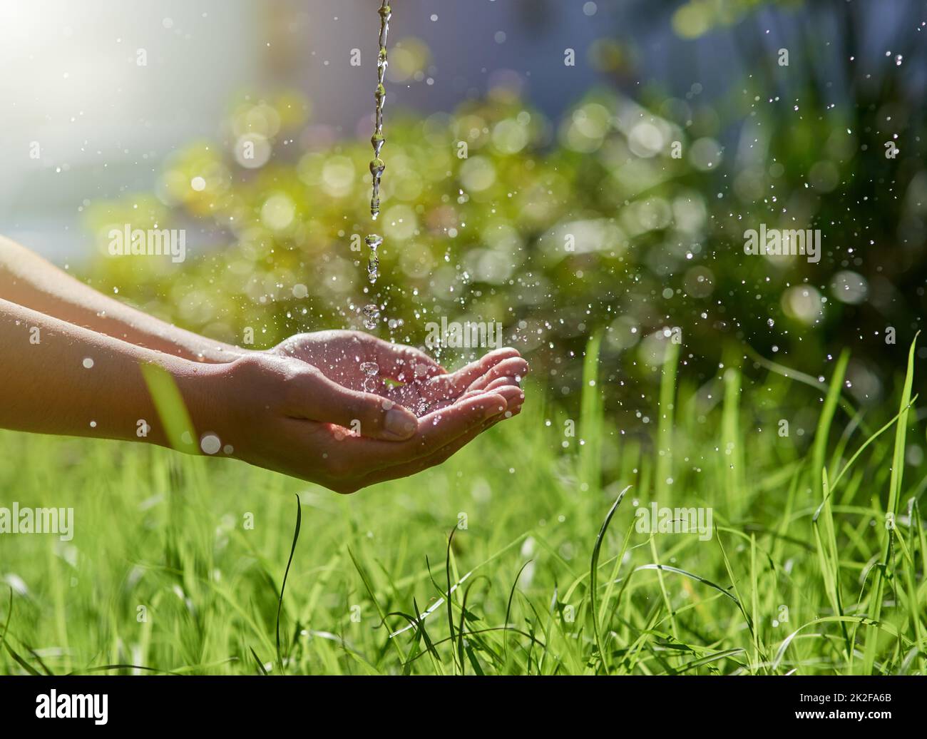 Natures most precious resource. Shot of hands held out to catch a stream of water outside Stock