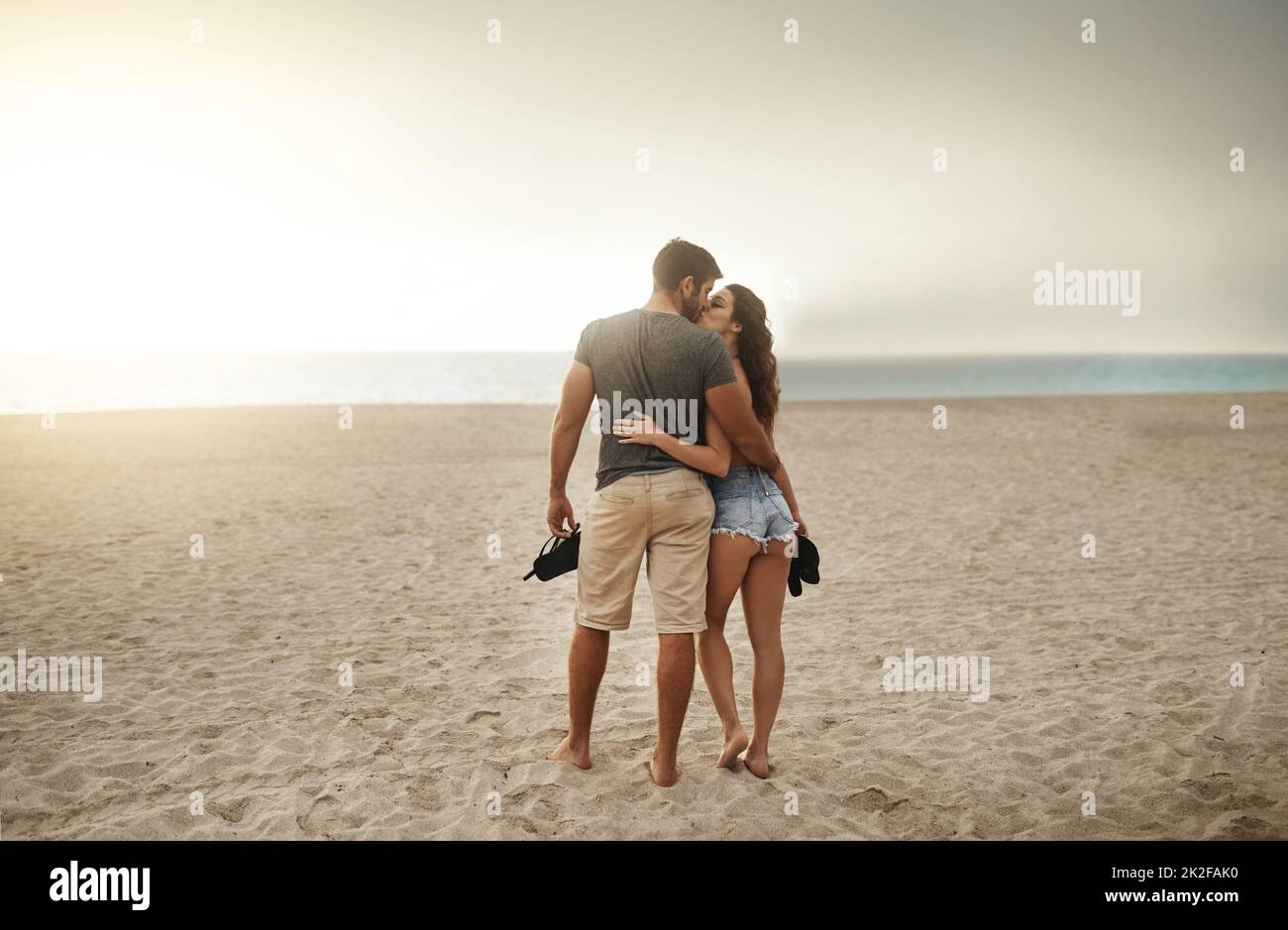 Romantic seaside strolls at sundown. Shot of a young couple spending a romantic day at the beach. Stock Photo