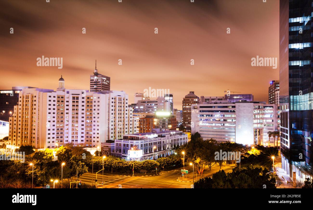 Twilight descends on the city. Shot of a city with lights coming on as