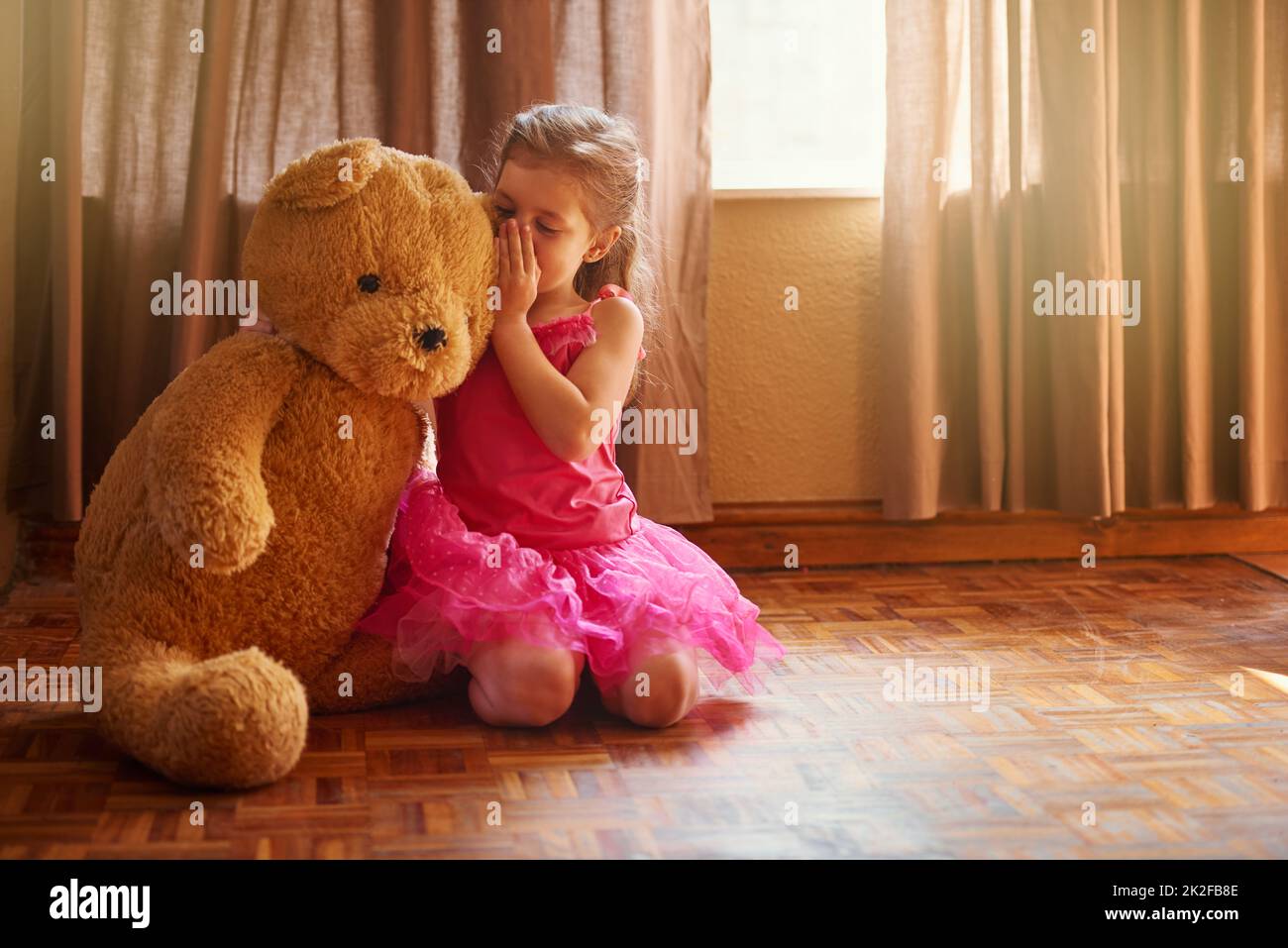 Teddy is the only one who can keep a secret. Shot of a little girl whispering something in her teddy bears ear. Stock Photo