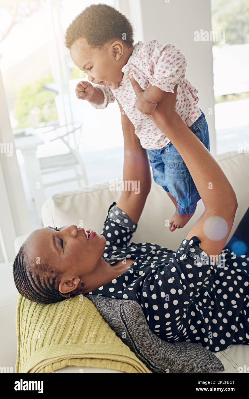 Mommys little angel. Shot of a mother holding her baby girl up in the air. Stock Photo