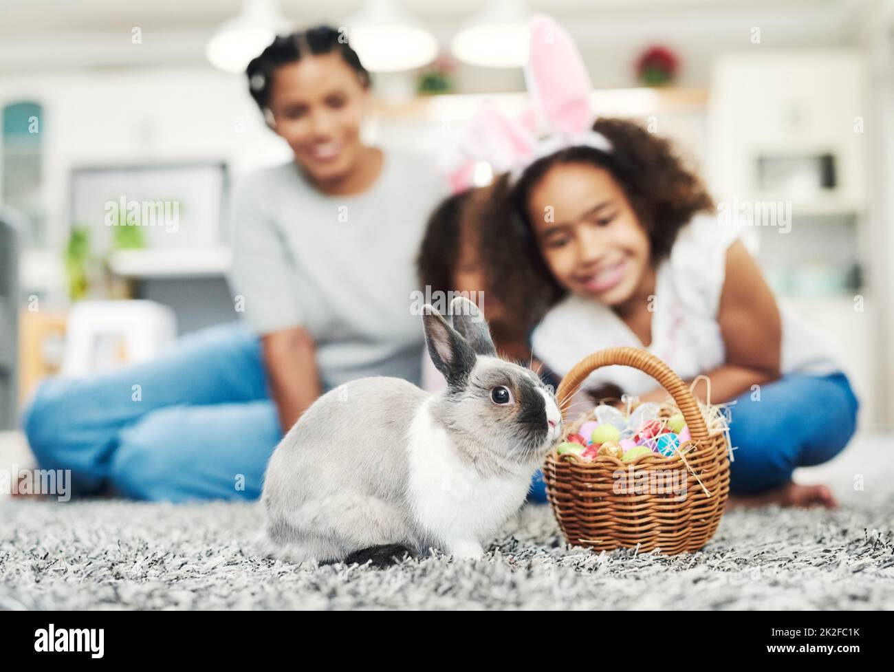 Ears hoping you have a very hoppy Easter. Shot of a little girl playing with a rabbit at home. Stock Photo