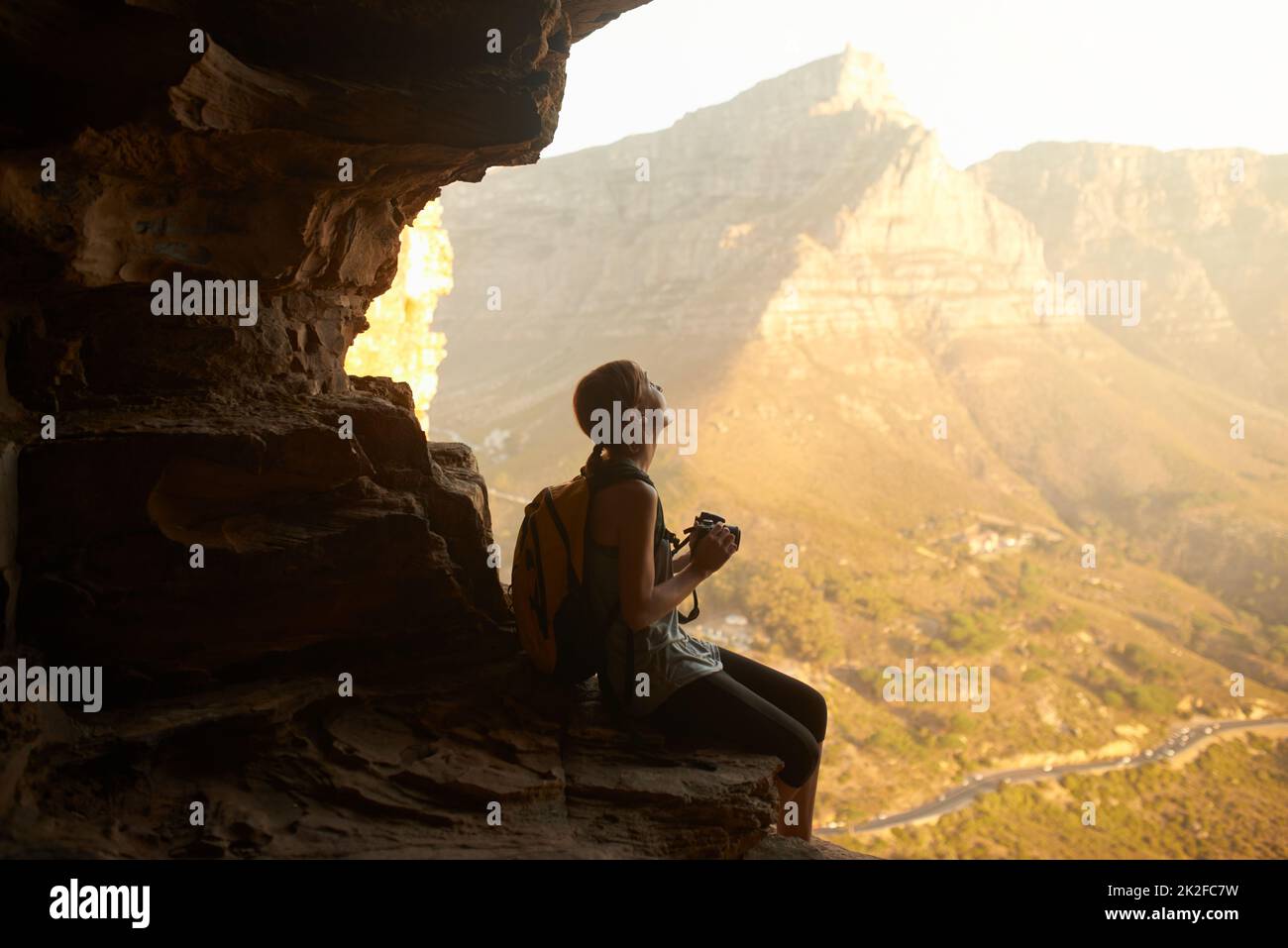 The memories are worth the climb. Shot of a woman taking a picture with her camera on top of a mountain. Stock Photo