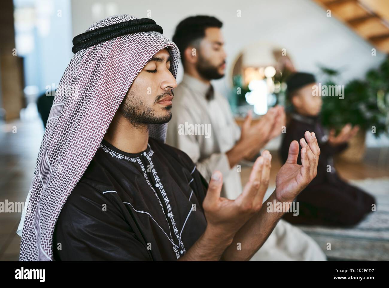 Prayer with a thankful heart. Shot of a group of muslim male family members praying together. Stock Photo