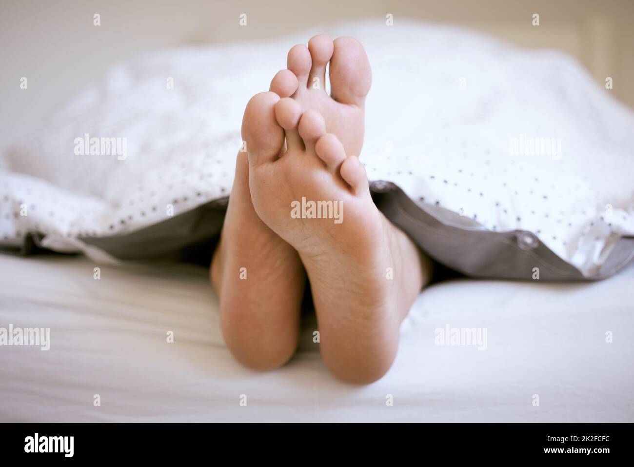 Sleeping is mandatory on weekends. Shot of an unrecognizable mans feet