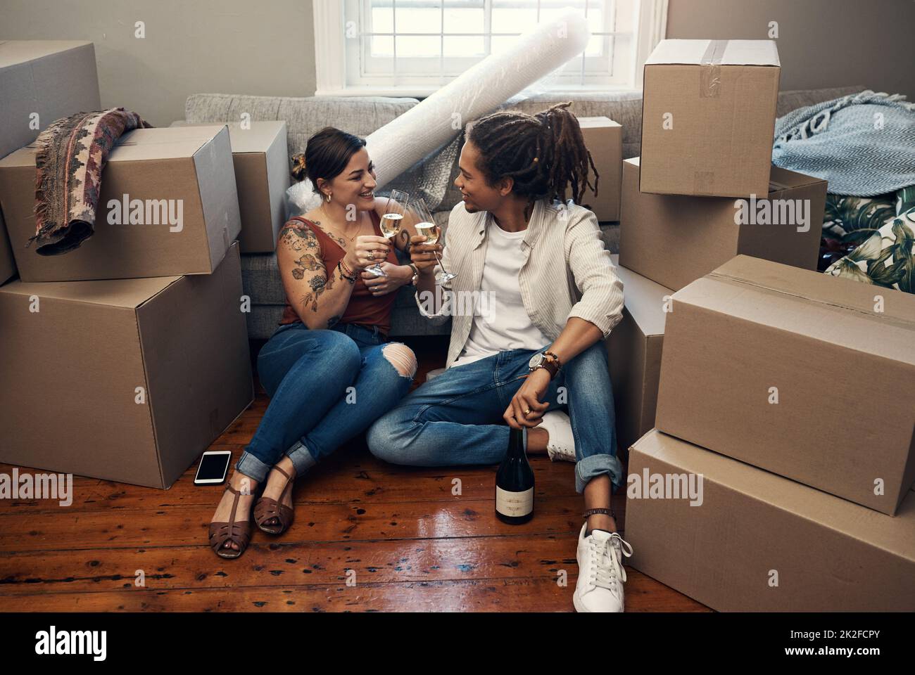 We really deserve it, babe. Shot of a happy young couple having champagne to celebrate their new home. Stock Photo