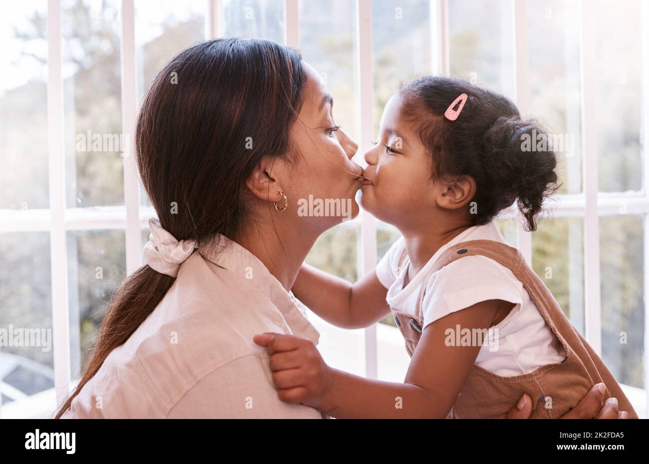 Kisses for my good girl. Shot of a young mother giving her daughter a kiss at home. Stock Photo