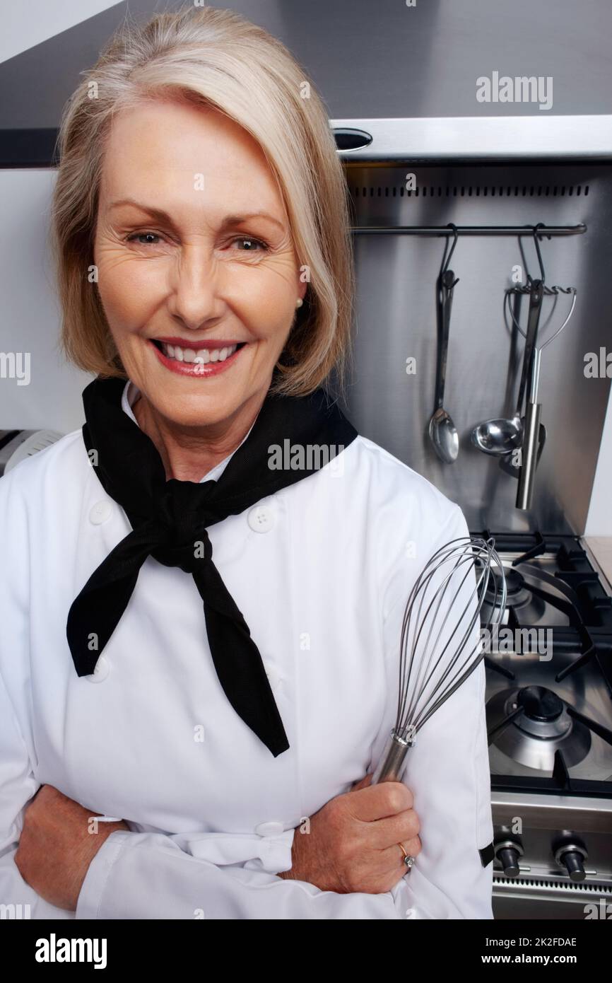 Female chef holding wire whisk standing in front of gas stove. Closeup