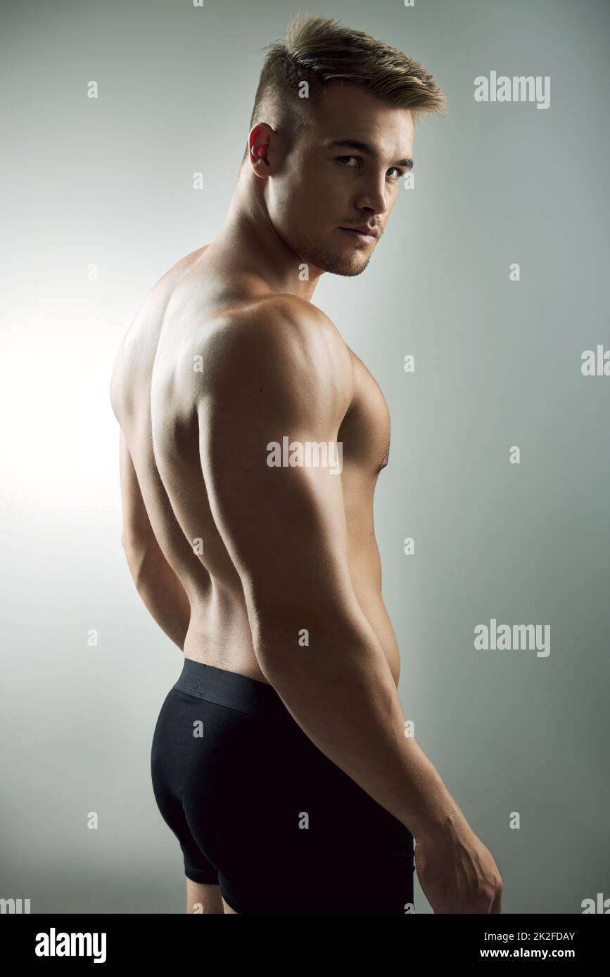 My body is my brand. Studio portrait of a muscular young man posing against a grey background. Stock Photo