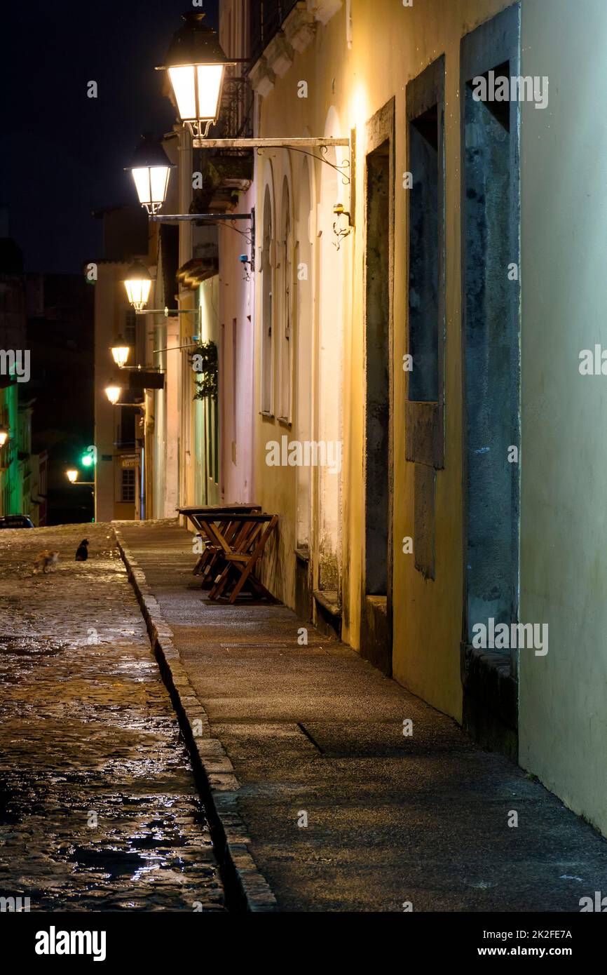 Old cobblestone street with colonial houses lit at night Stock Photo ...