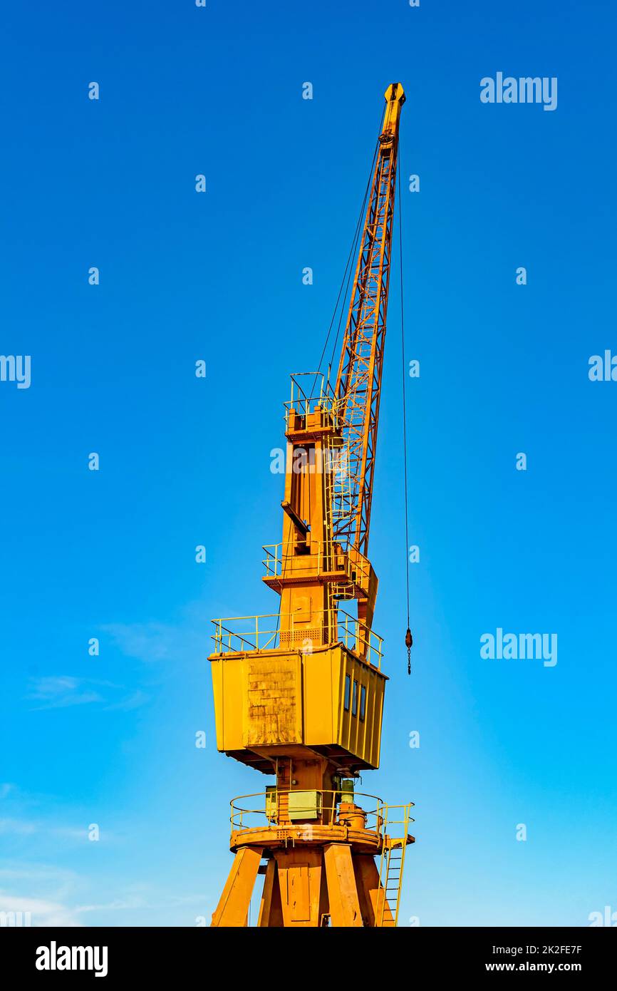 Old and obsolete yellow crane lit by the afternoon sun Stock Photo