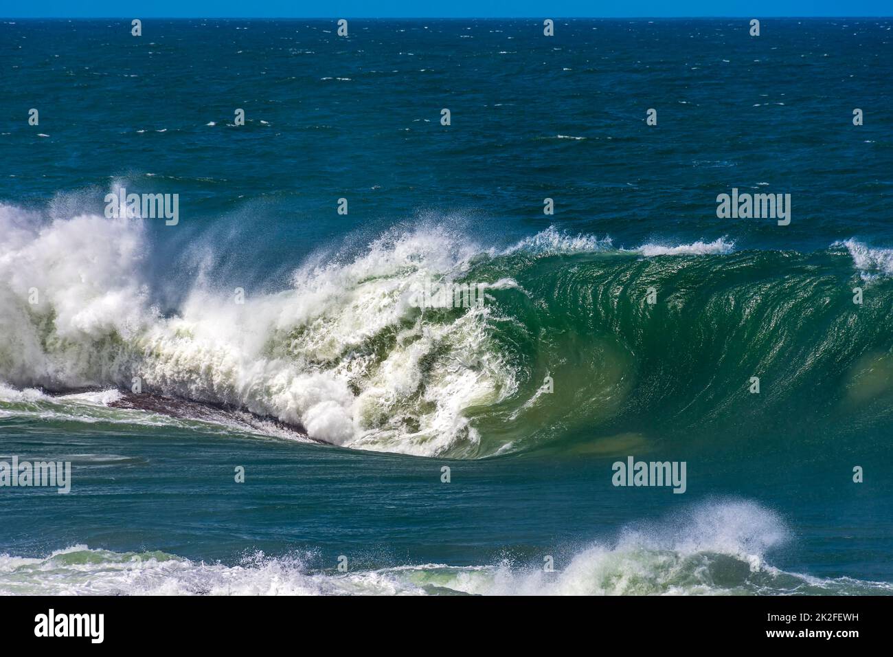 Wave breaking during stormy weather on a sunny day Stock Photo