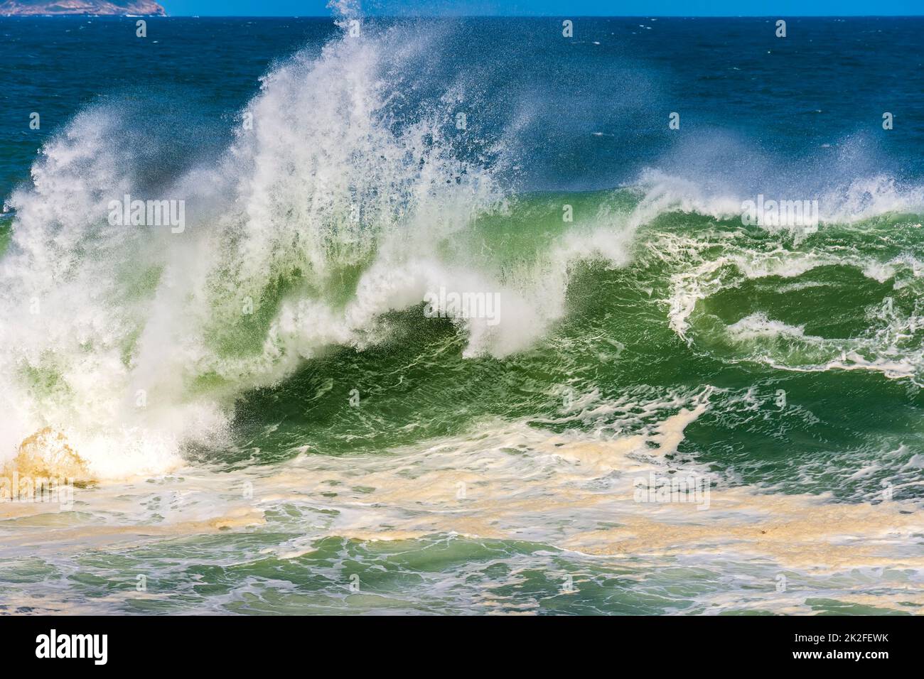 Wave crashing during stormy weather on a sunny day Stock Photo