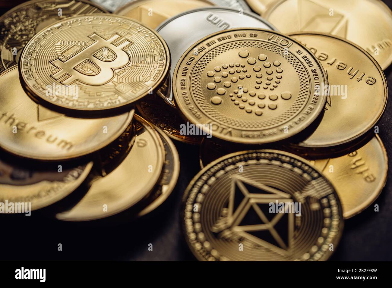 Close up shot of a golden Bitcoin, Cardano and Ethereum in a stack, among other various digital cryptocurrencies . Stock Photo