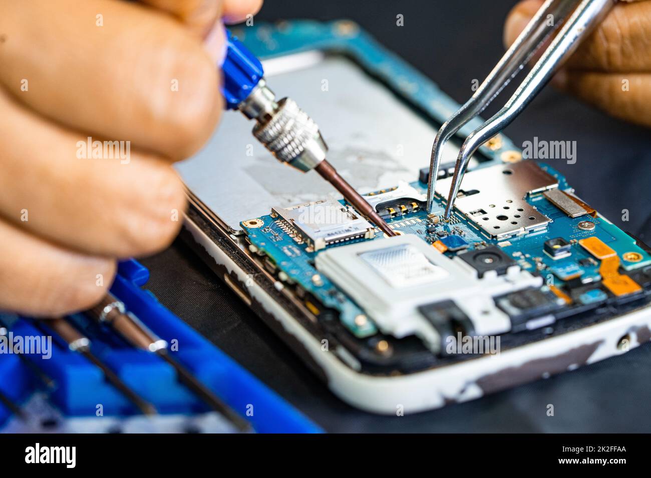 Technician repairing inside of mobile phone by soldering iron