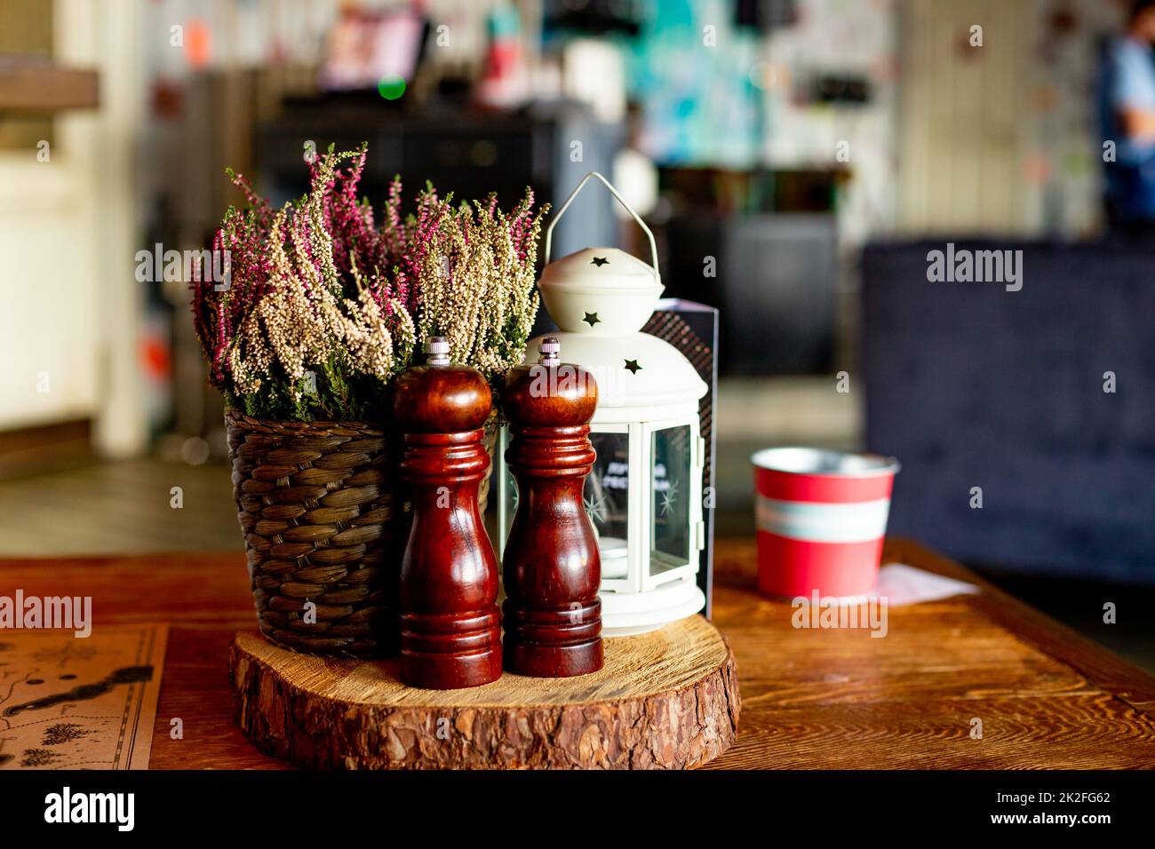 Wooden traditional salt and pepper shakers in cafe,selective focus.Still life details of cozy interior in rustic style.Wooden spices shakers, mills Stock Photo