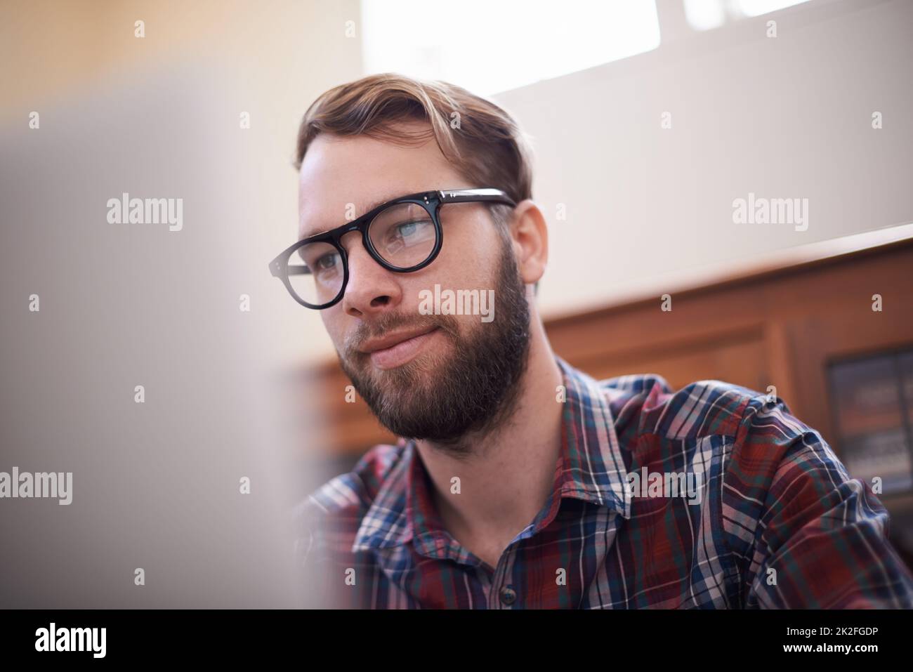 Using all the latest tech. a handsome young hipster working on a laptop. Stock Photo