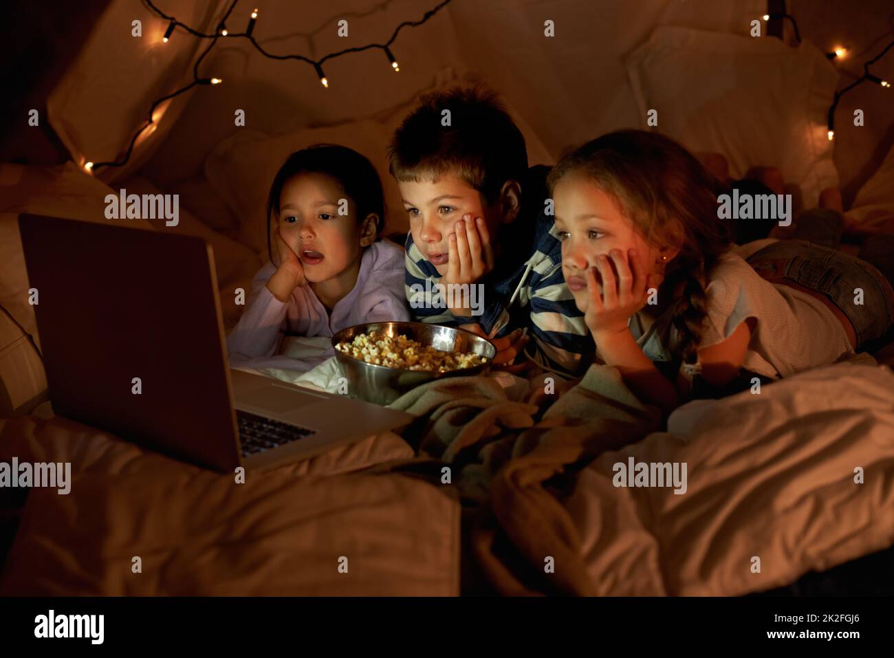 Our pillow for is the bomb. three young children using a laptop in a blanket fort. Stock Photo