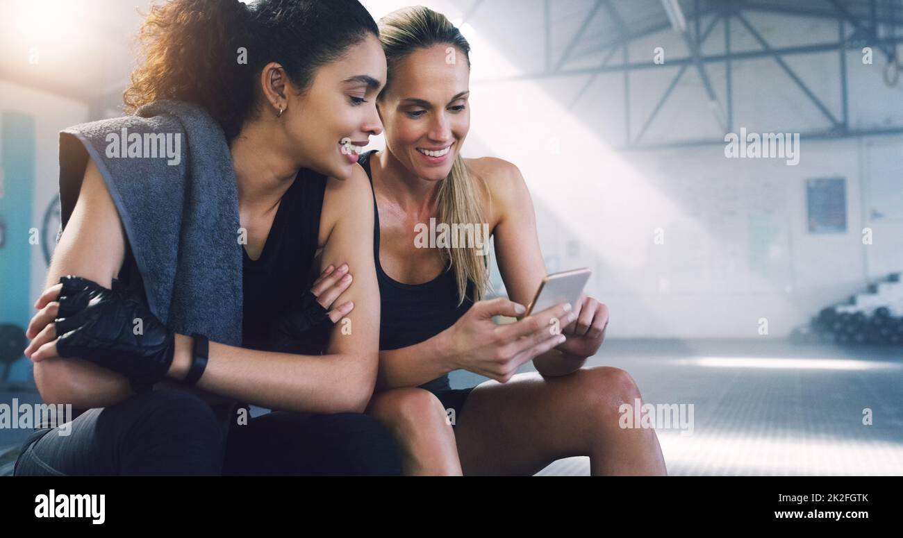 Keeping up with the latest, anywhere, anytime. Cropped shot of two attractive sportswomen in the gym sitting down and reading text messages. Stock Photo