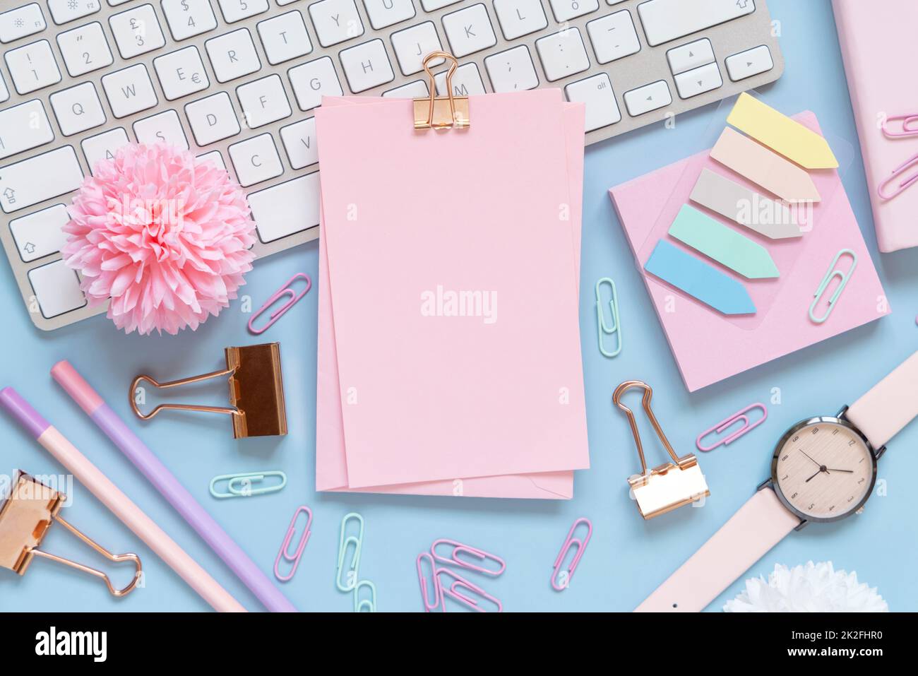 Paper with a clip, Pink school girly accessories and keyboard on light blue Top view, mockup