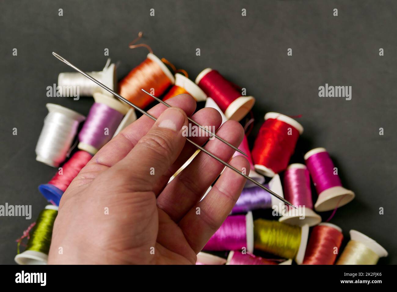 classic sewing needle and threads in a tailor's hand,sewing needle