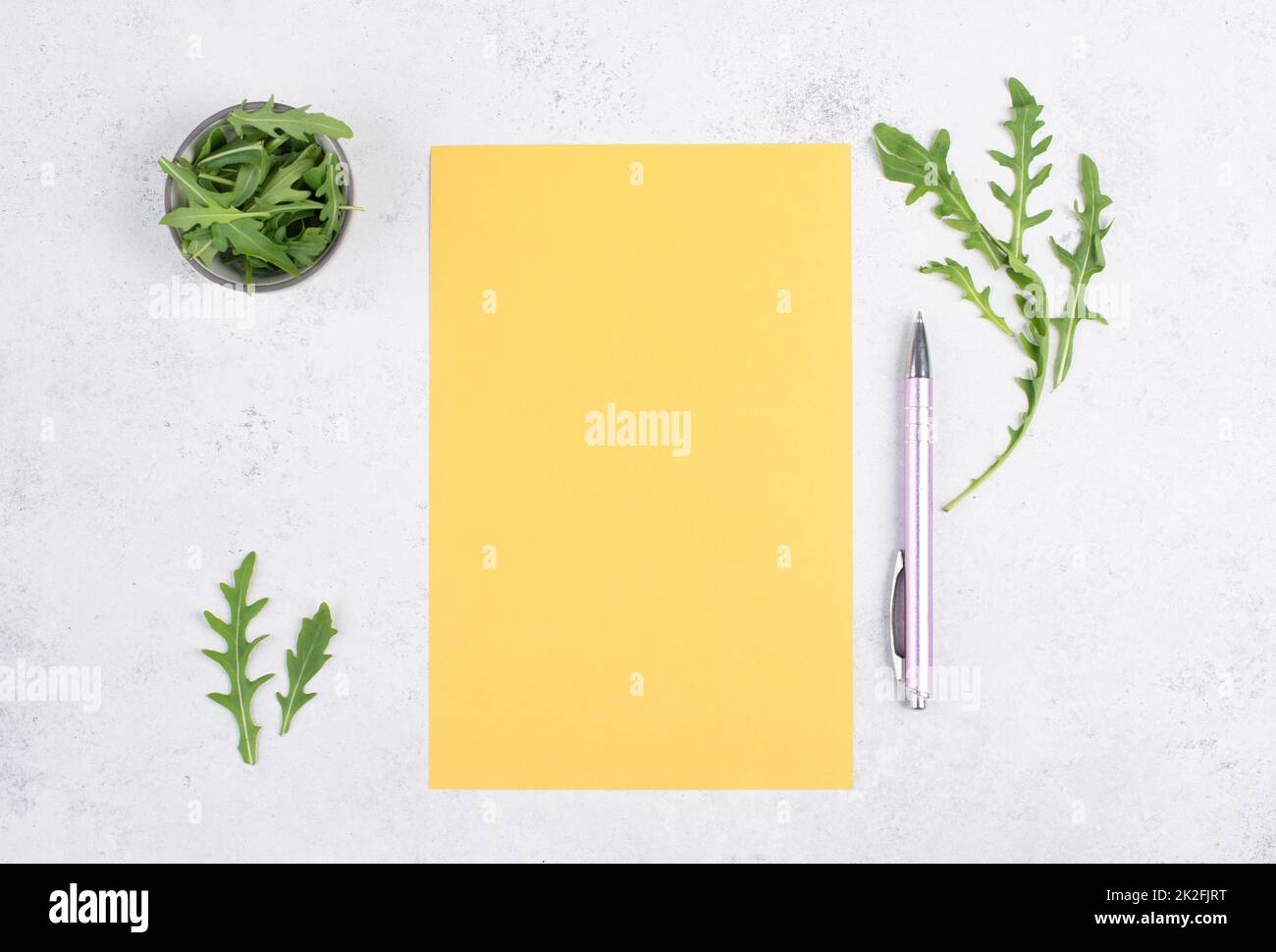 Blank colored paper with a pen, arugula salad leaves, copy space for text, recipe for cooking, preparing food, healthy lifestyle, diet Stock Photo