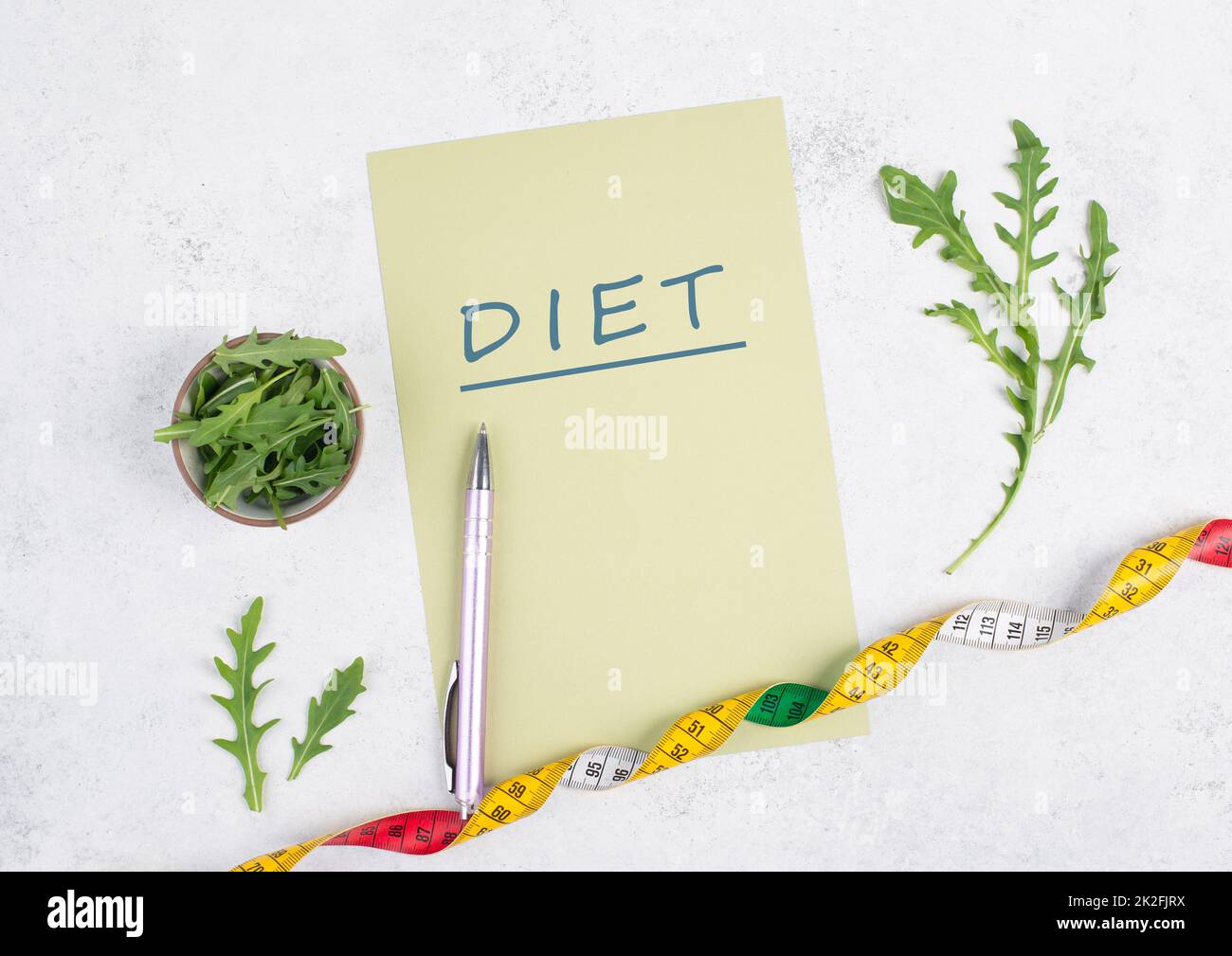 On the paper stands diet plan, arugula salad and tailor tape measure around the note, healthy food and lifestyle, loosing weight Stock Photo