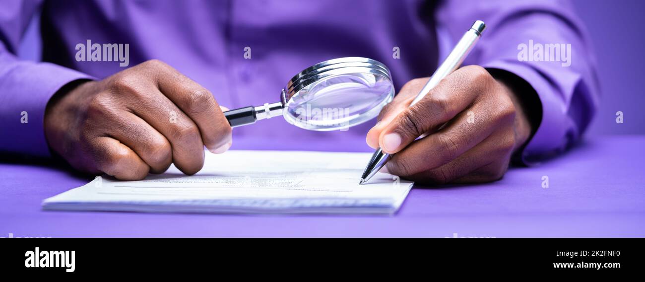 Auditor Using Magnifying Glass For Audit And Fraud Investigation Stock