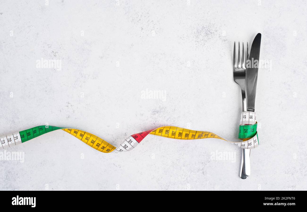 Fork tight with a tape measure, copy space for text, making a diet, loosing weight, staying hungry, healthy lifestyle Stock Photo