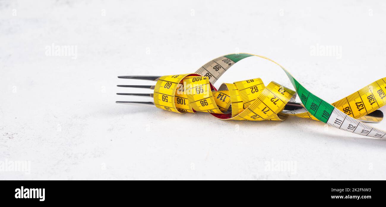 Fork tight with a tape measure, copy space for text, making a diet, loosing weight, staying hungry, healthy lifestyle Stock Photo