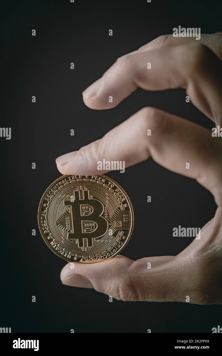 Close up shot of human fingers holding a silver bitcoin digital cryptocurrency. Stock Photo