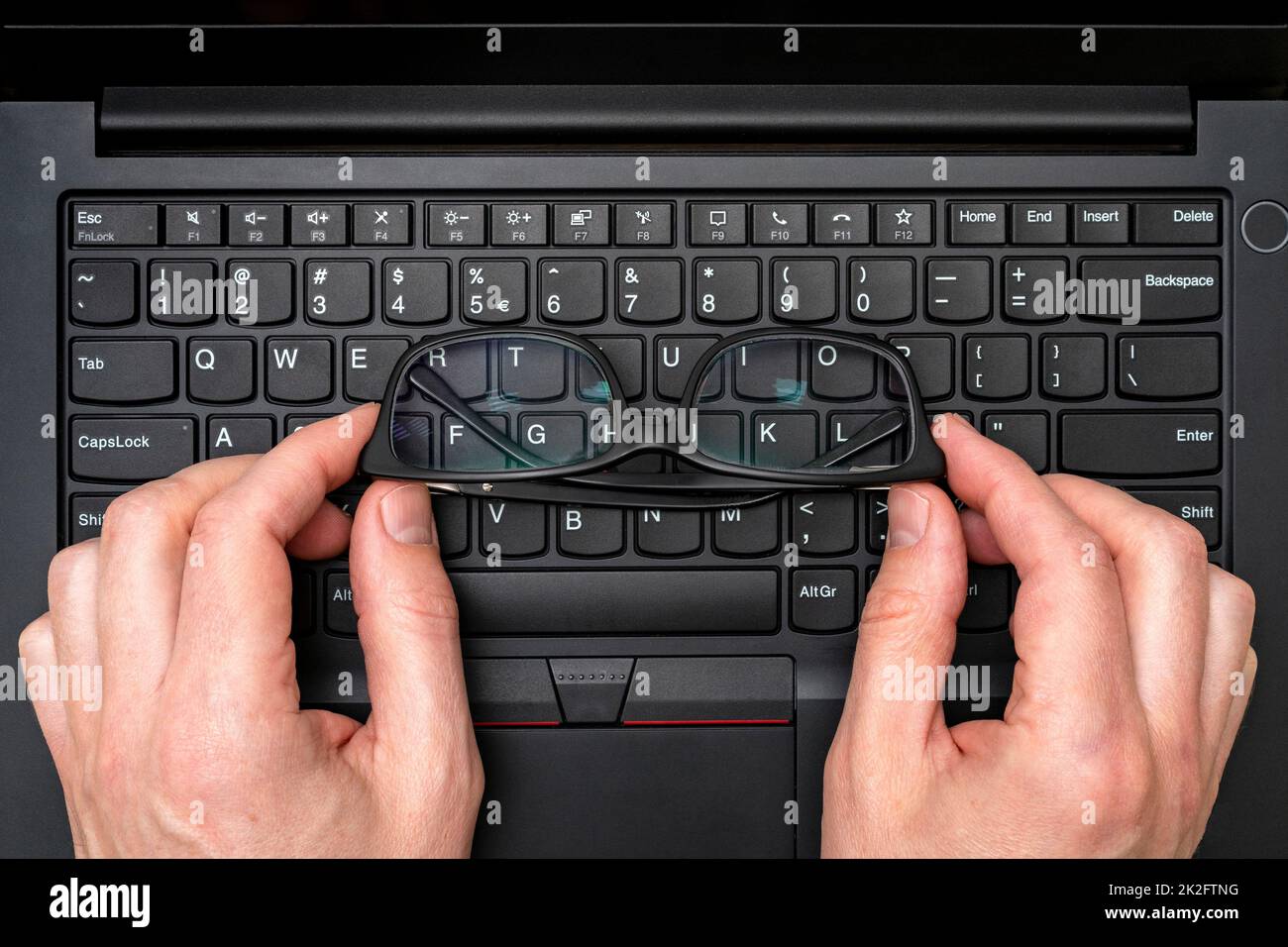 Hands holding glasses on laptop keyboard Stock Photo