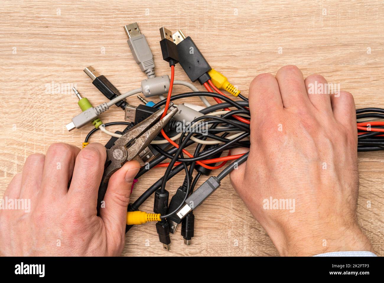 Hands of the master hold wire cutters and bundle of computer cables Stock Photo