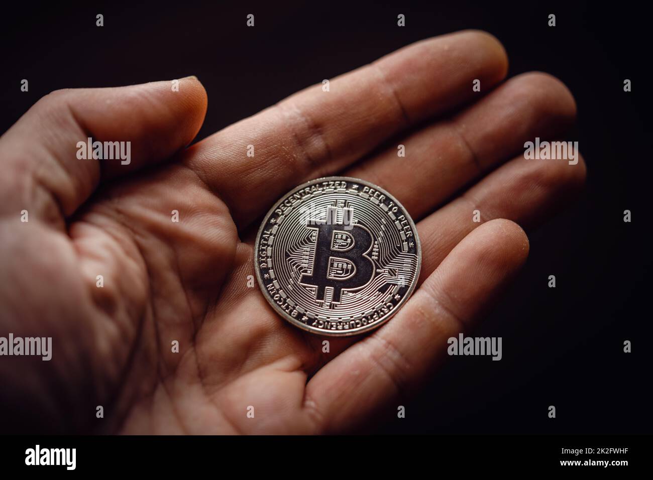 Close up shot of hand holding a silver bitcoin digital cryptocurrency. Stock Photo