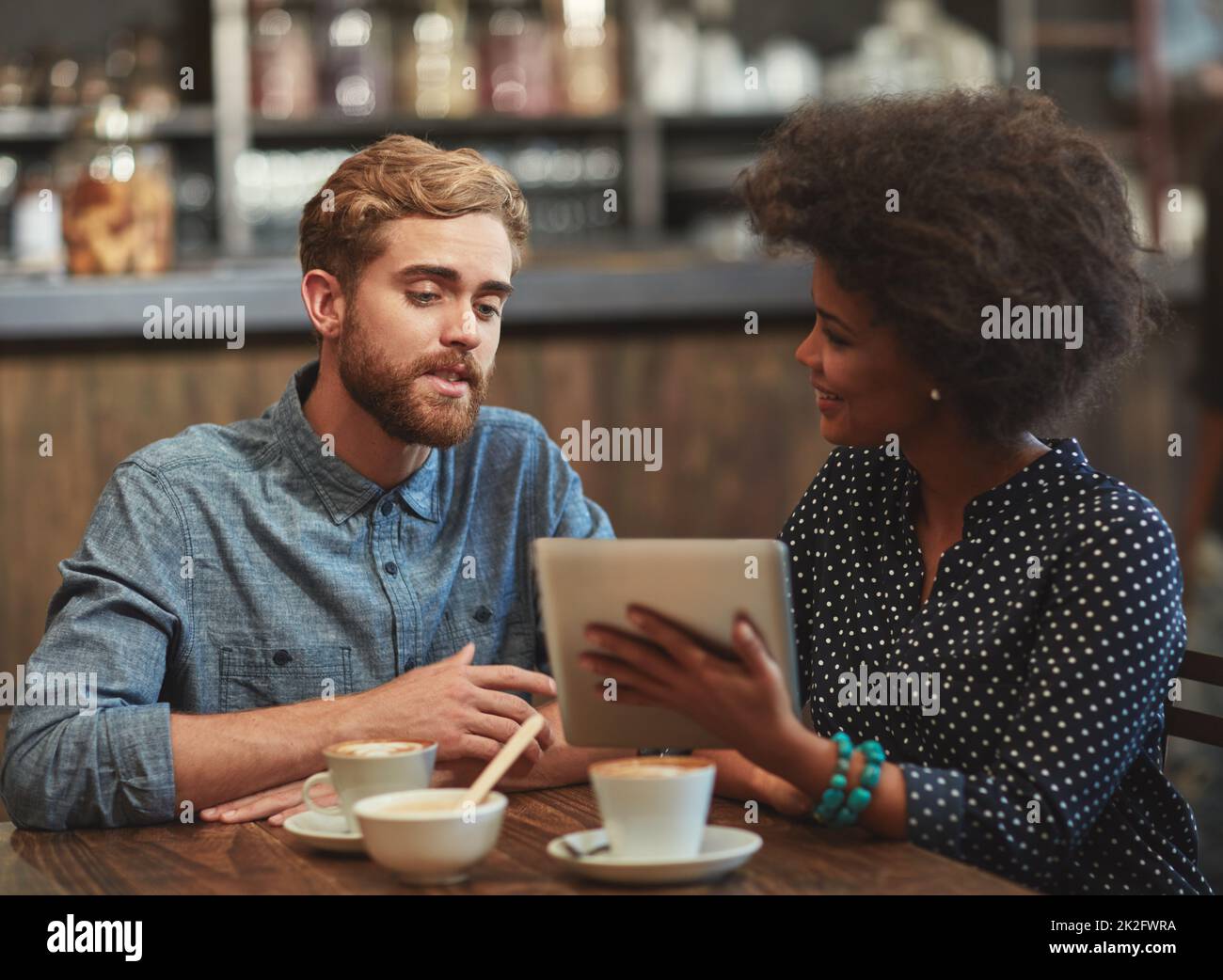 Discussing new ideas for their coffee shop. Shot of a young couple using a digital tablet together on a coffee date. Stock Photo