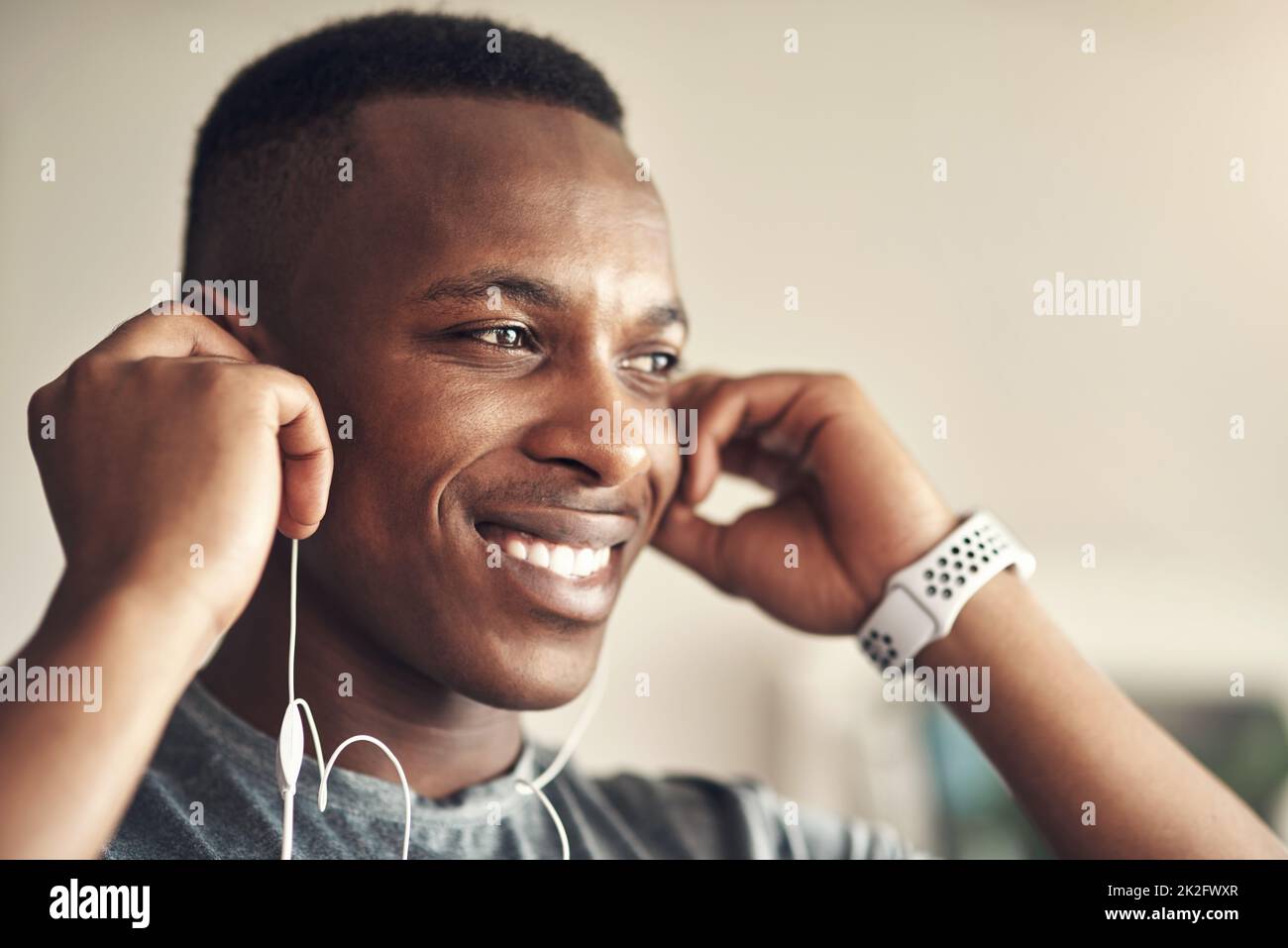 The right tunes keep me pumped with energy. Shot of a sporty young man listening to music while exercising at home. Stock Photo