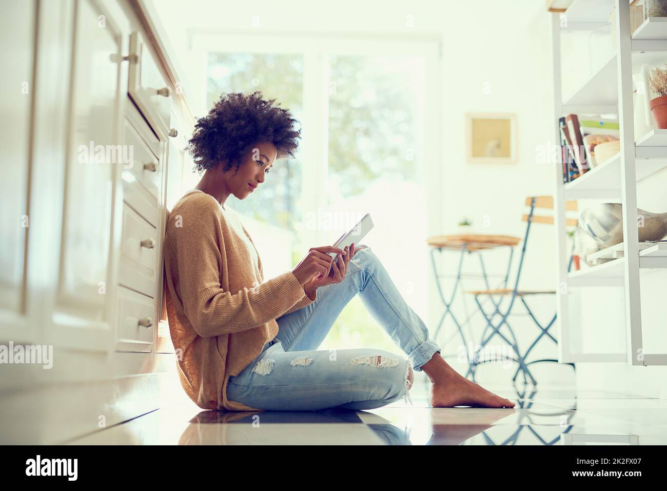 Getting stuck into that ebook shes been wanting to read. Shot of a young woman using a digital tablet at home. Stock Photo