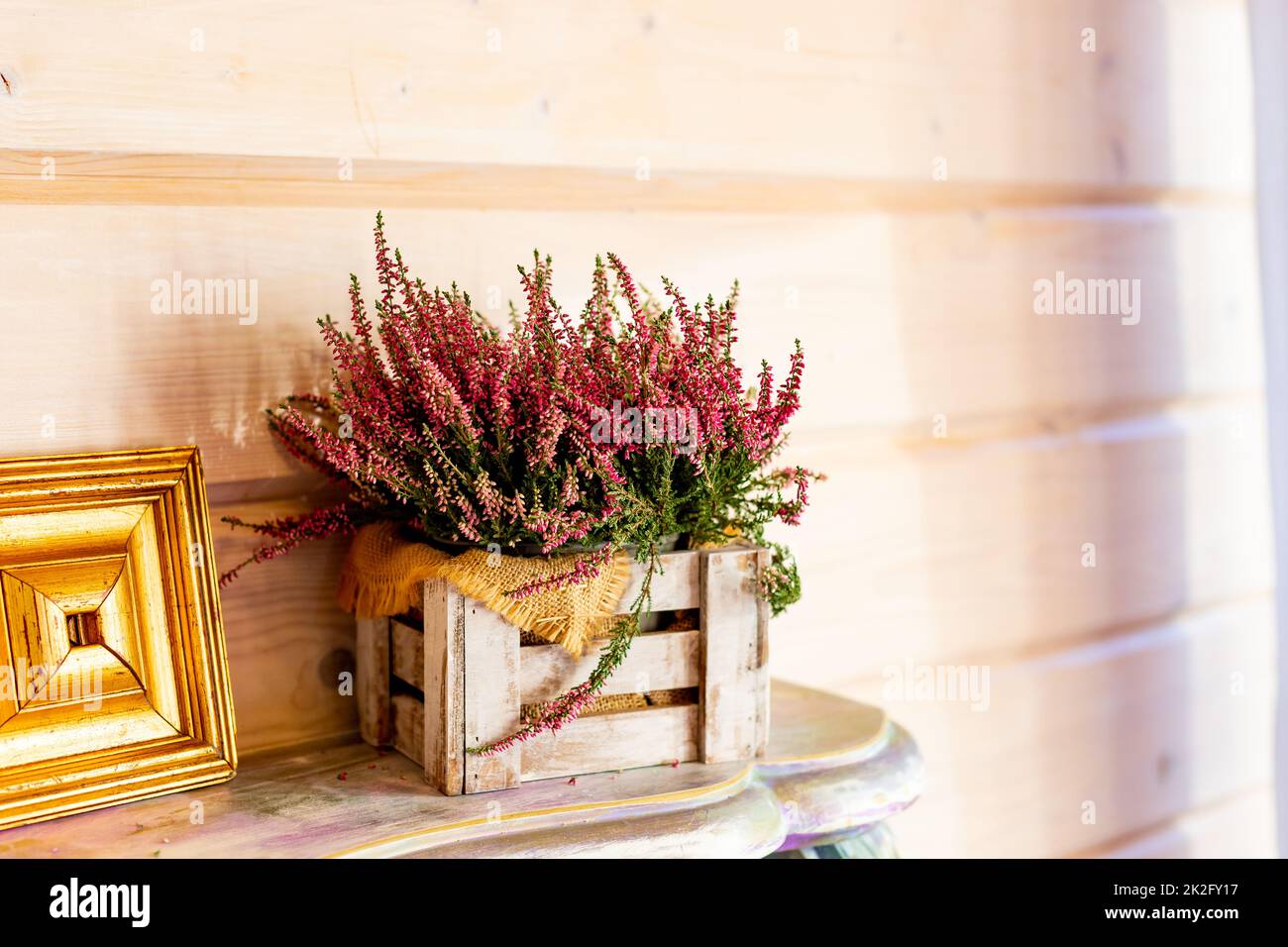 home balcony decor with pink heather flowers in wooden box, candlelight flame, autumn hygge home decor.Still life details of cozy interior in rustic Stock Photo