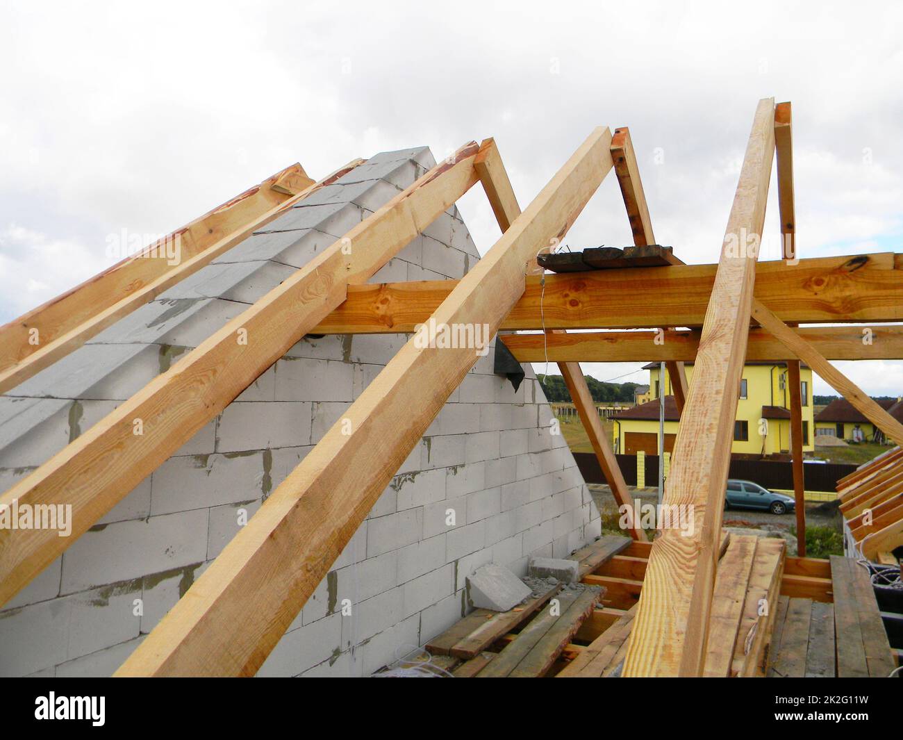 House roof top wooden frame construction. Unfinished house roofing construction wooden beams, trusses, timber. Stock Photo