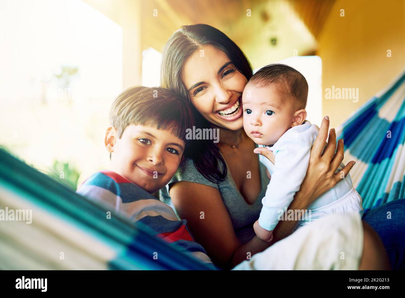 These two complete my life. Portrait of a cheerful mother relaxing on a hammock with her two little boys outside at home during the day. Stock Photo