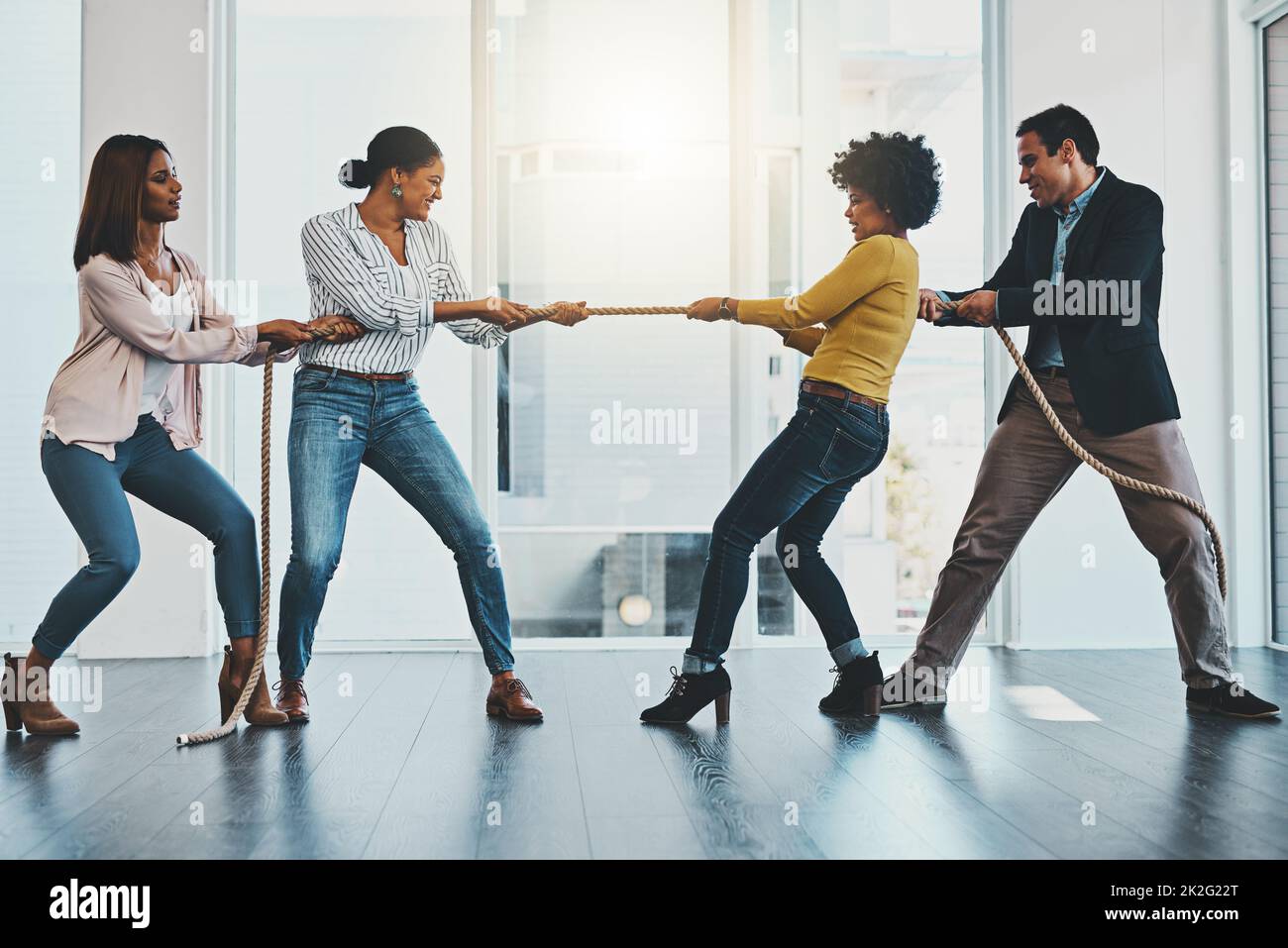 Its a competitive market out there with many challenges. Shot of a group of businesspeople pulling on a rope during tug of war in an office. Stock Photo