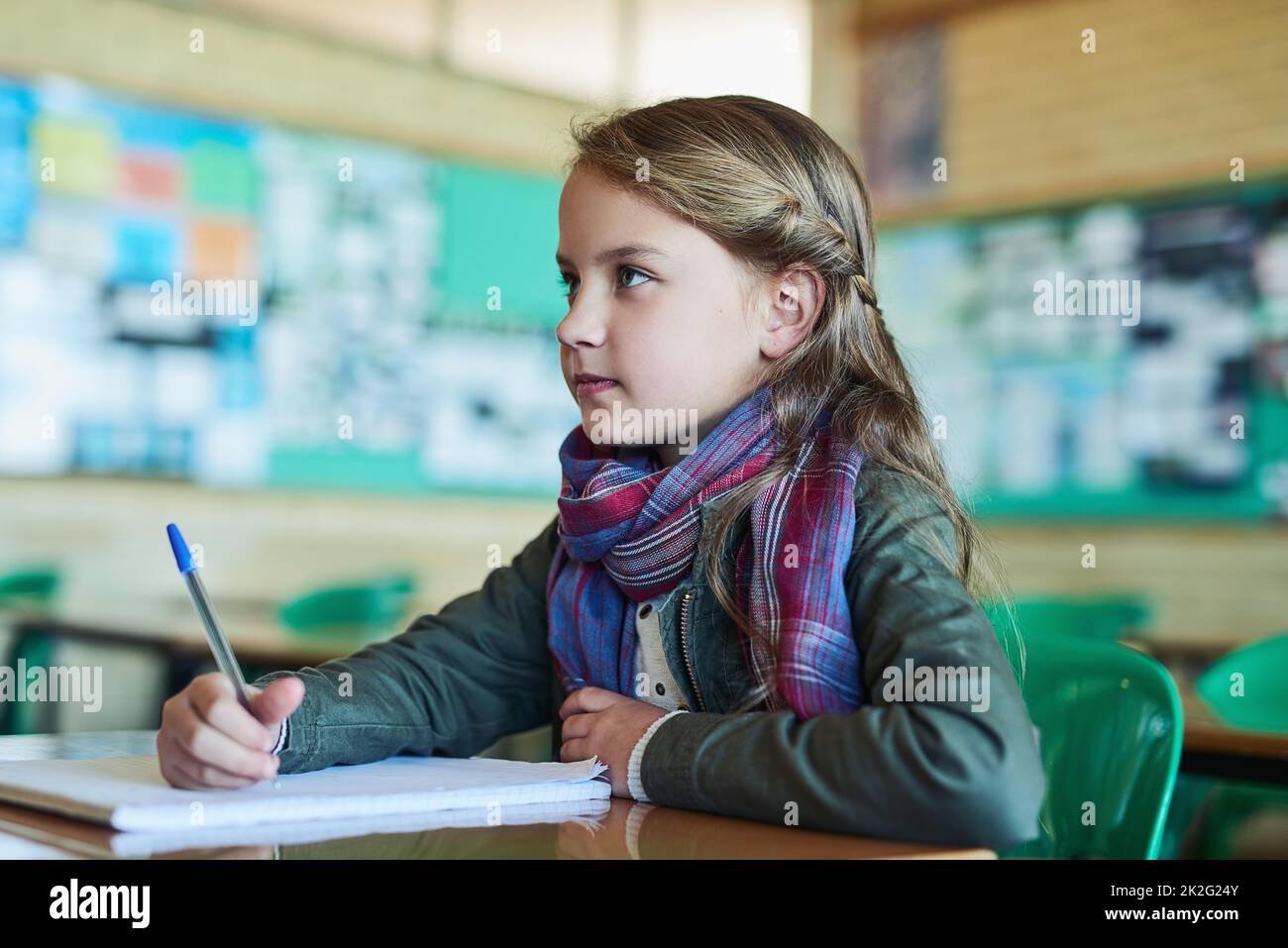 Listening carefully in class. Shot of an elementary school girl working in class. Stock Photo