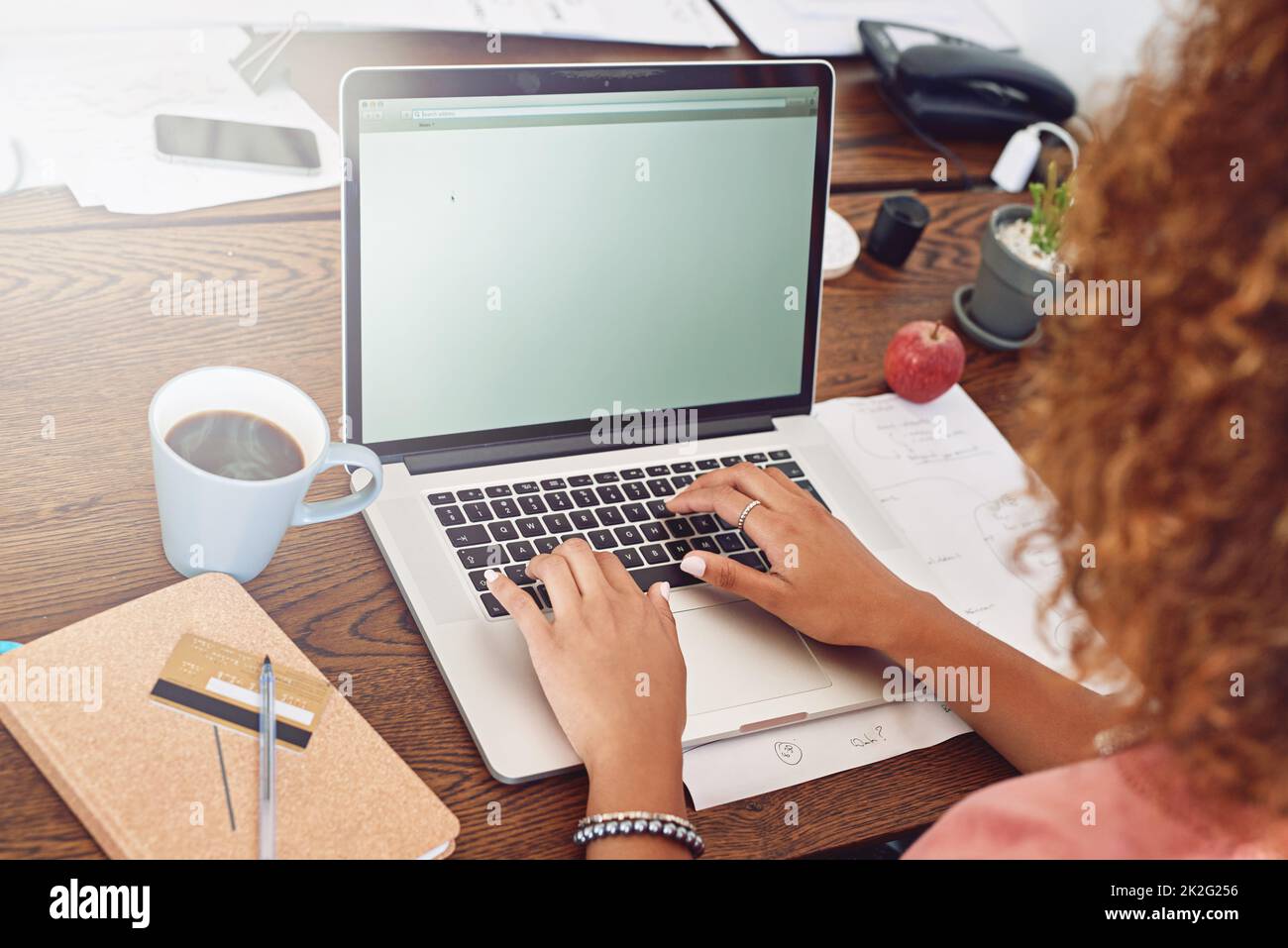 Doing some online stationary shopping. Cropped shop of a designer working on her laptop with her coffee and credit card in front of her. Stock Photo